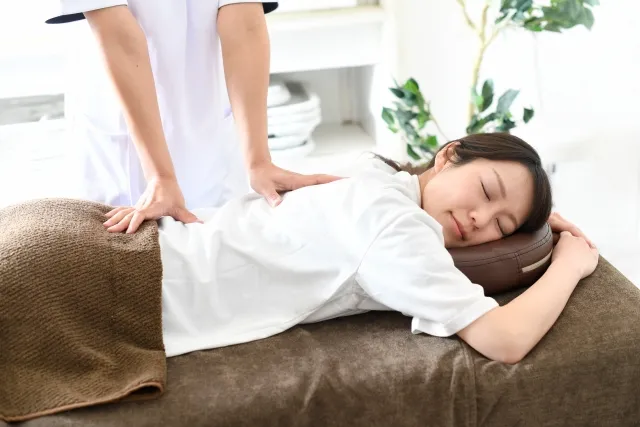 ベッドで整体を受け、腰まわりの緊張をゆるめる女性
